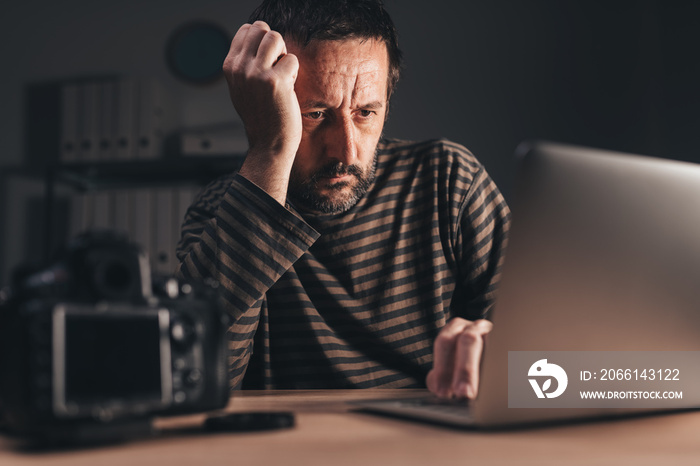 Photographer reviewing photos on laptop computer at his workplace