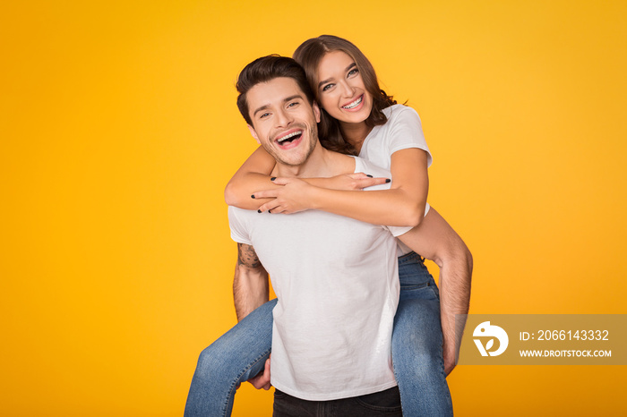 Lovely couple having fun, man piggybacking his girlfriend