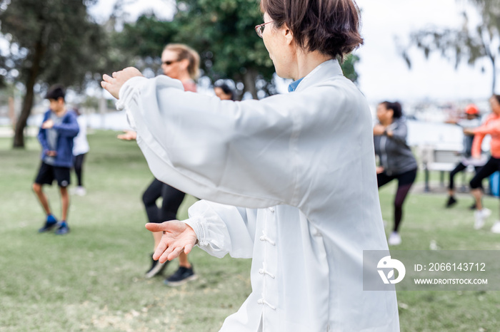 成熟的中国女人在公园里和一群人一起打太极