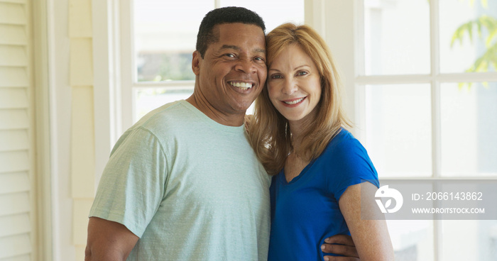 Smiling couple looking at camera and holding each other while laughing