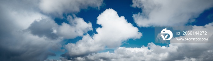 Clear blue sky with glowing white cumulus clouds. Midday sun. Panoramic dramatic cloudscape. Concept