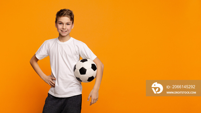 Boy posing with soccer ball on orange studio background