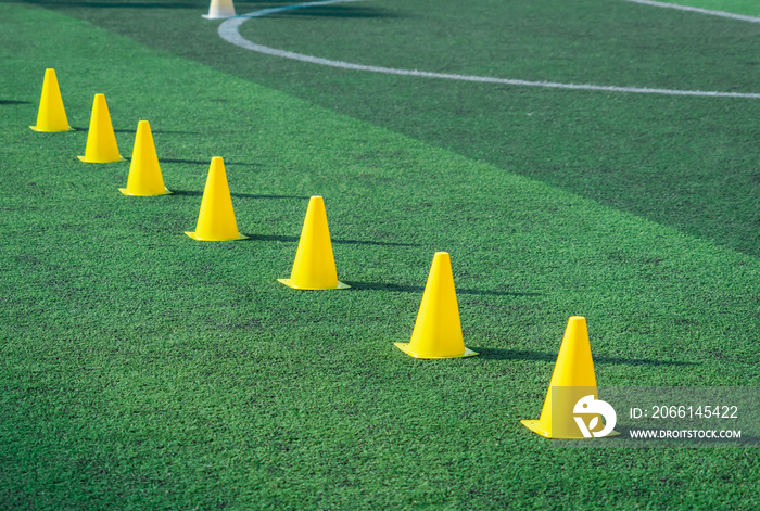 Yellow sport training cones marker on soccer green grass pitch for children football training sessio