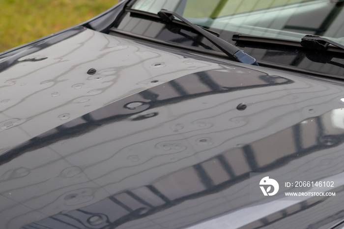 Car engine hood with many hail damage dents show the forces of nature and the importance of car insu