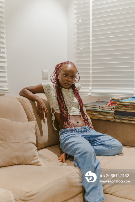 A black woman sitting on a couch posing for a portrait around records