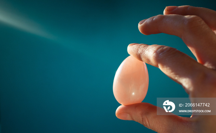 woman holding a pink quartz yoni egg