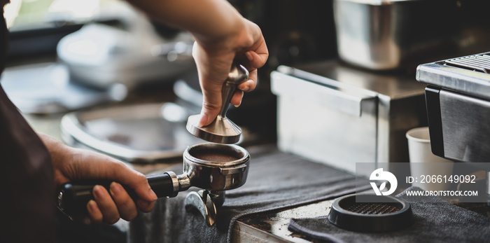 Close-up view of barista hands grinding coffee