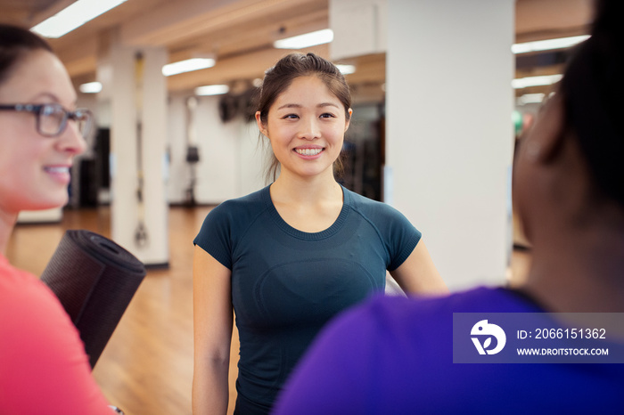 Smiling female athletes talking in yoga class