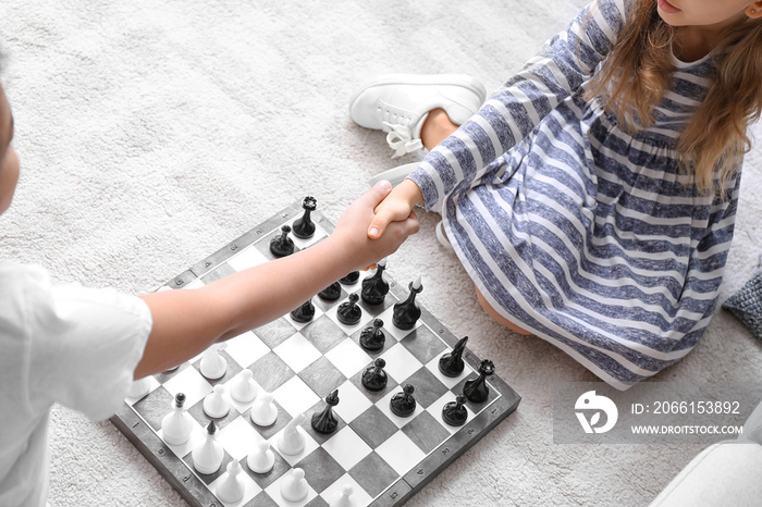 Cute children playing chess at home