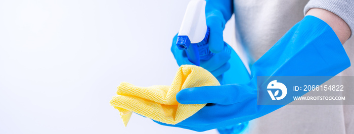 Young woman housekeeper in apron is cleaning, wiping down table surface with blue gloves, wet yellow