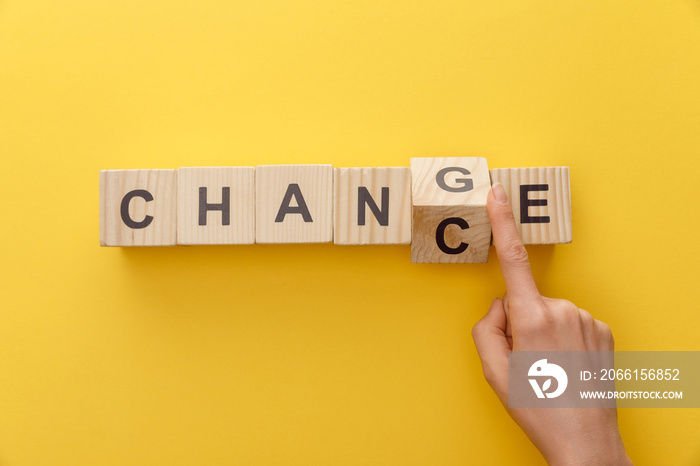 cropped view of woman switching wooden cube from word change to chance on yellow background