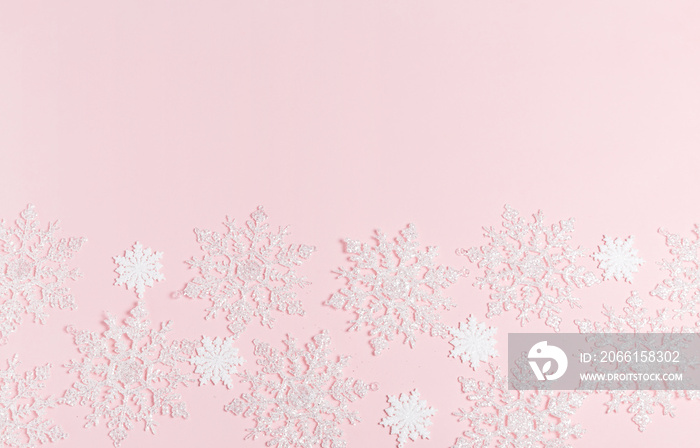 Christmas composition. Frame made of balls and snowflakes on pastel pink background.