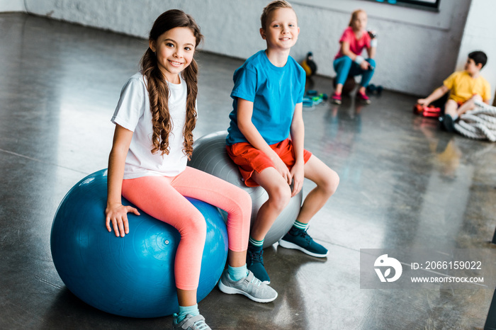 Preteen kids sitting on fitness balls and looking at camera