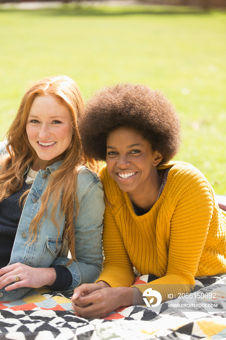 Portrait happy young women friends relaxing on blanket in sunny park