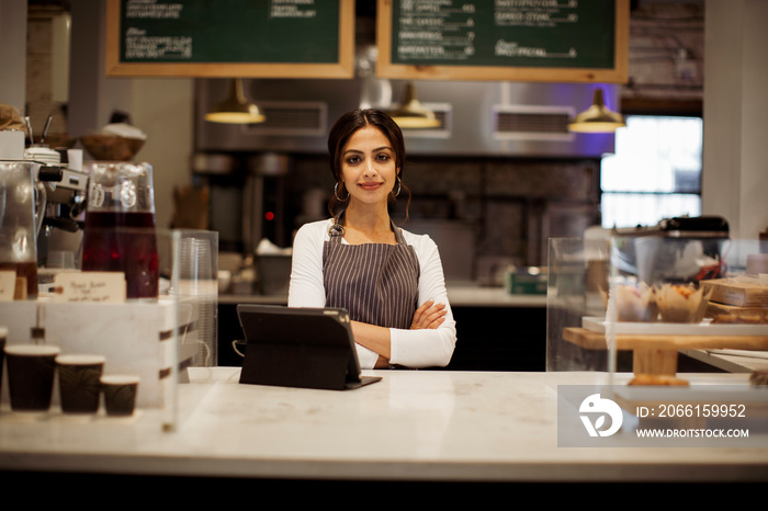 Portrait of smiling female manager with tablet computer on bar counter standing in cafe