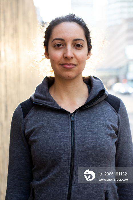 Portrait of confident female athlete standing on sidewalk in city