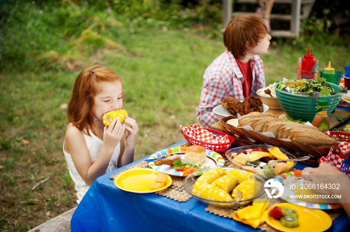 Siblings eating at picnic table