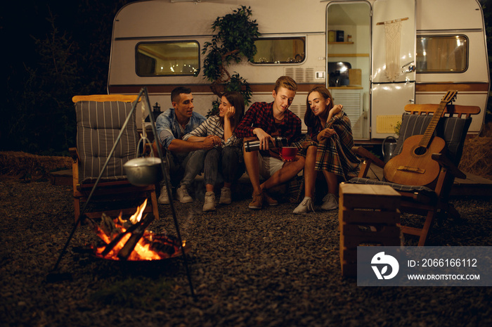 Friends sitting by campfire in the night, camping