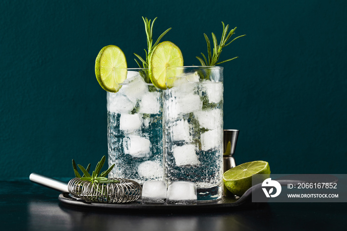 classic gin and tonic cocktail with rosemary sprigs in tall glasses on a table with bar accessories