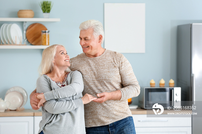 Portrait of happy mature couple dancing in kitchen