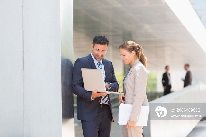 Corporate business people using laptop outdoors