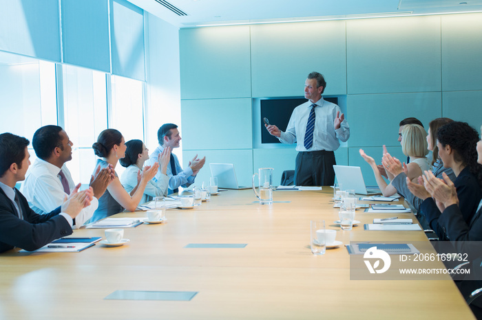 Corporate business people clapping for businessman leading meeting