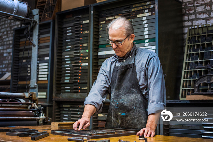 Senior craftsman working with letterpress in workshop