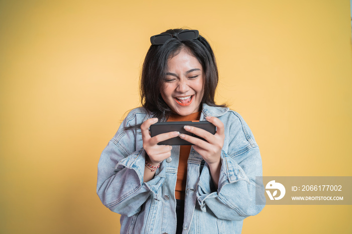 asian girl laughing while playing game using cell phone