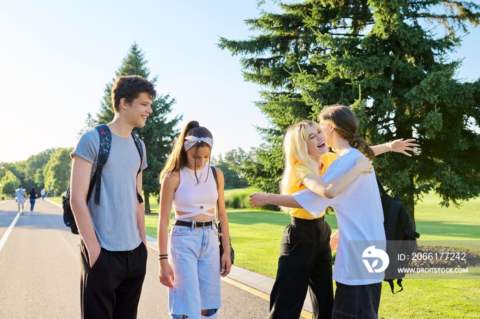 Meeting of smiling teenage friends in a sunny summer park