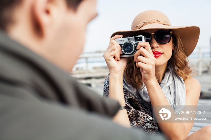 Young woman photographing boyfriend on coastal pier, Cape Town, Western Cape, South Africa