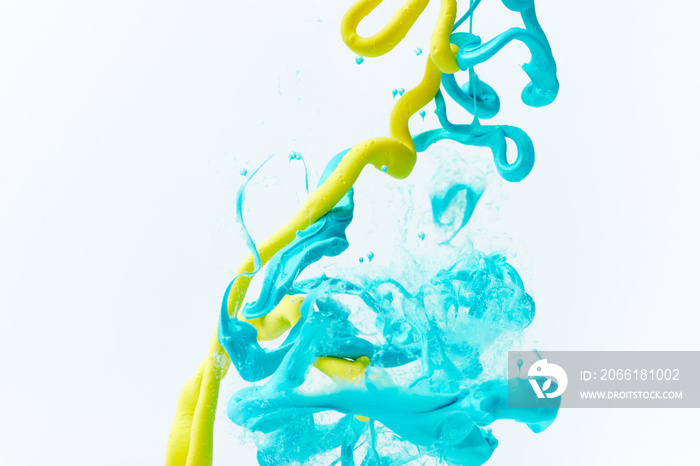在水中绘制白色飞溅曲线。丙烯酸蓝和黄色油漆滴背景。抽象颜色