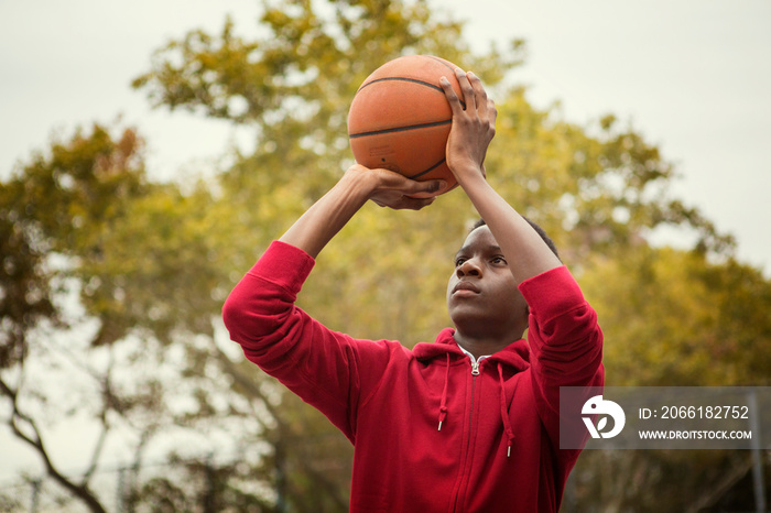 Teenage boy (14-15) playing basketball