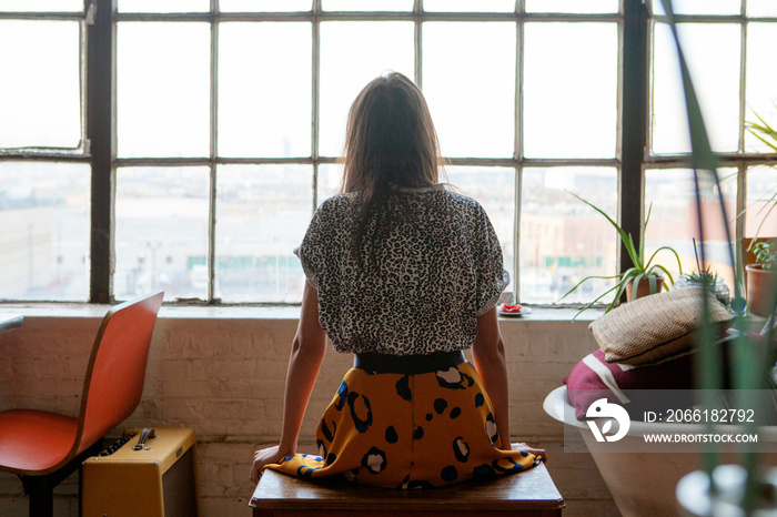 Young woman looking through window