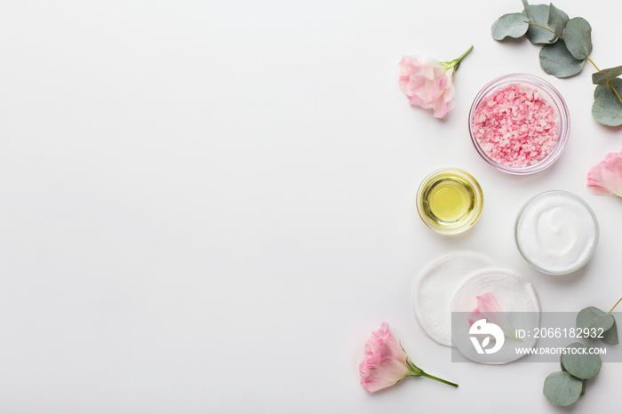 Sea salt with rose essential and face cream on white background