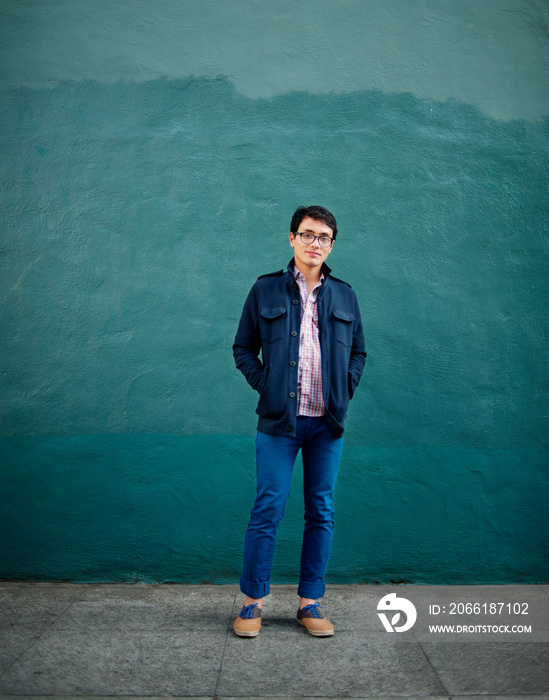 Portrait of young man standing in front of wall