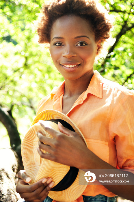Young woman holding hat in park