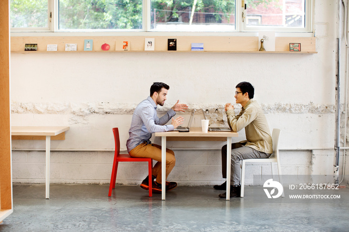 Two men talking at table in cafe