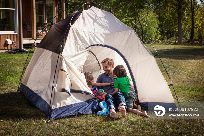 Father playing with daughters (4-5) in tent