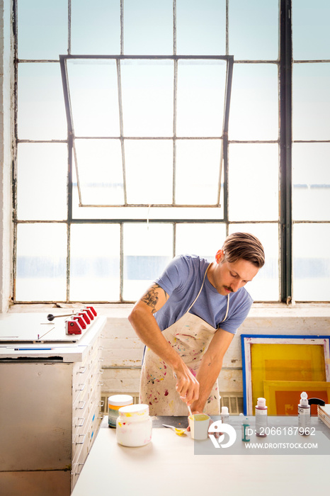 Man painting wood in workshop