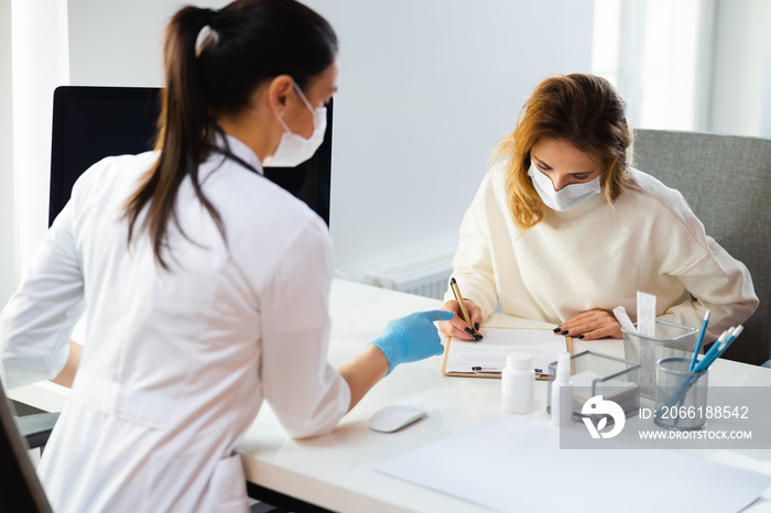 Caucasian mother in medical mask writng permission on treatment