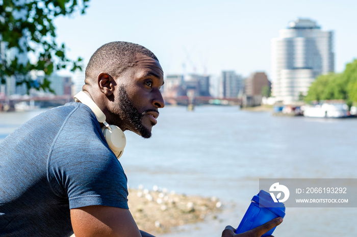 Man holding plastic water container and looking at city river