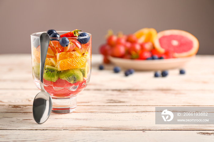 Glass with tasty fruit salad on table