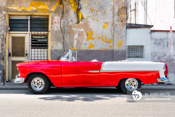 Classic red convertible car next to a shabby building in Old Havana