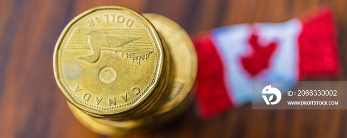 Stack of Canadian 1 dollar Loonies with Canadian flag - Panorama