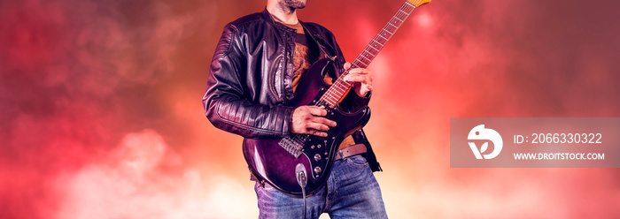 Rock guitarist plays solo on an electric guitar. Artist and musician performs like rockstar. Guitar player performs on stage.