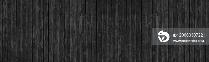 Old black knotted wooden board wide panoramic texture. Dark gray rough wood plank long backdrop. Large abstract background