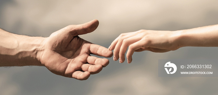 Hands of man and woman reaching to each other, support. Hands of man and woman on blue sky background. Giving a helping hand. Lending a helping hand. Solidarity, compassion, and charity, rescue