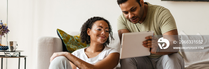 Middle eastern man and woman talking while using tablet computer and laptop