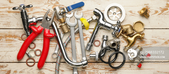 Set of plumber’s items on light wooden background, top view