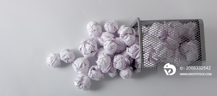 A trashcan full of crumpled paper on white background close up